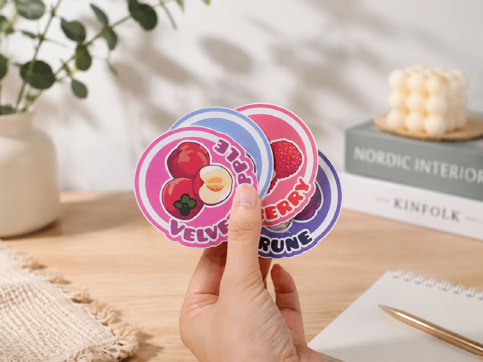 Hand holding colorful custom gloss vinyl stickers in a bright workspace
