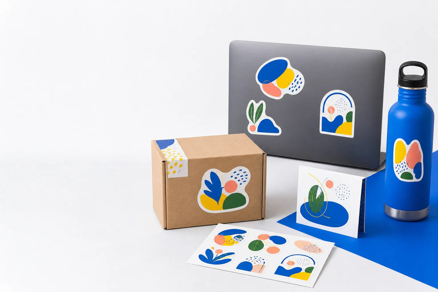 Custom stickers applied across packaging, a laptop, a reusable bottle and a sticker sheet